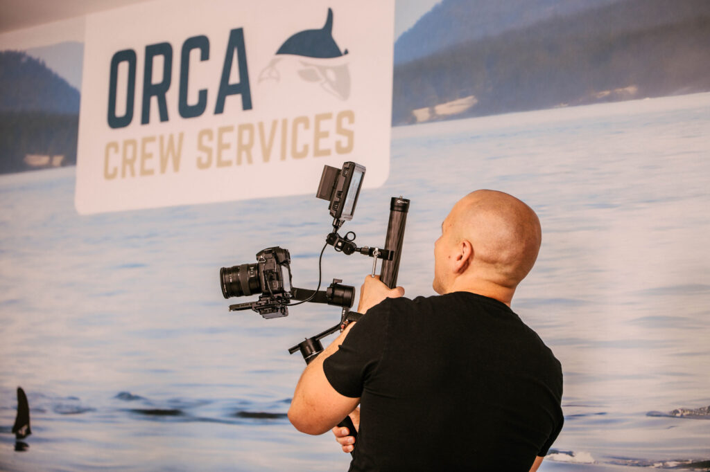Operatorius filmuoja prie ORCA Crew Services iškabos