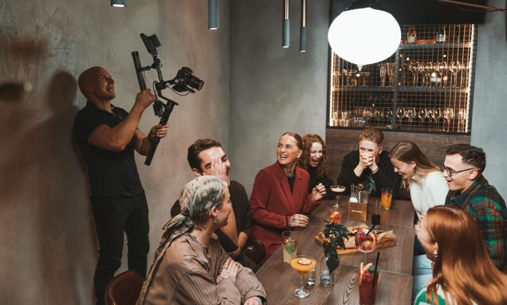 Operatorius filmuoja žmonių grupę restorane