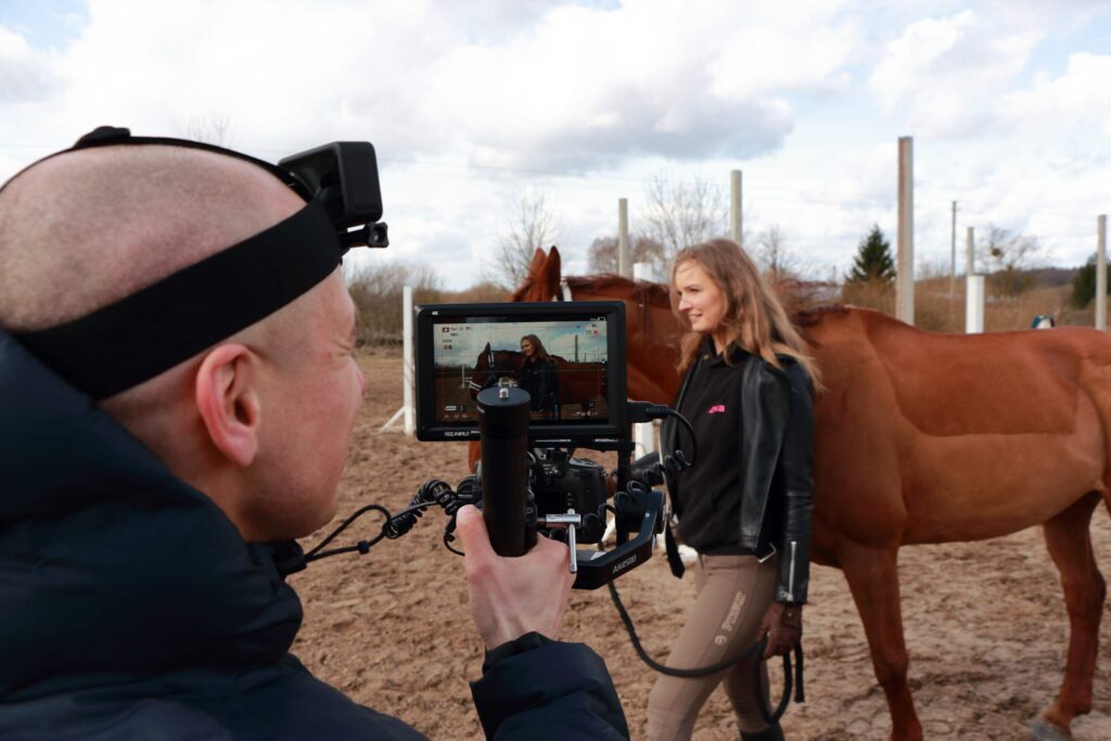 Videografas filmuoja moterį su žirgu