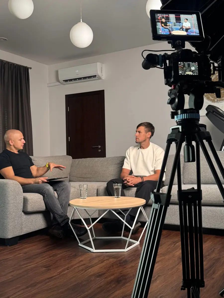 Eugenijus Mačiukas kalbina Povilą Klusaitį ilgo interviu filmavimo metu, priekyje kamera ant trikojo